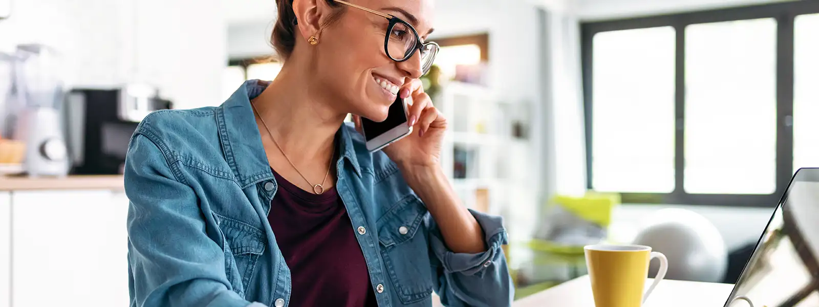 Woman Talking on the Phone While Using a Laptop