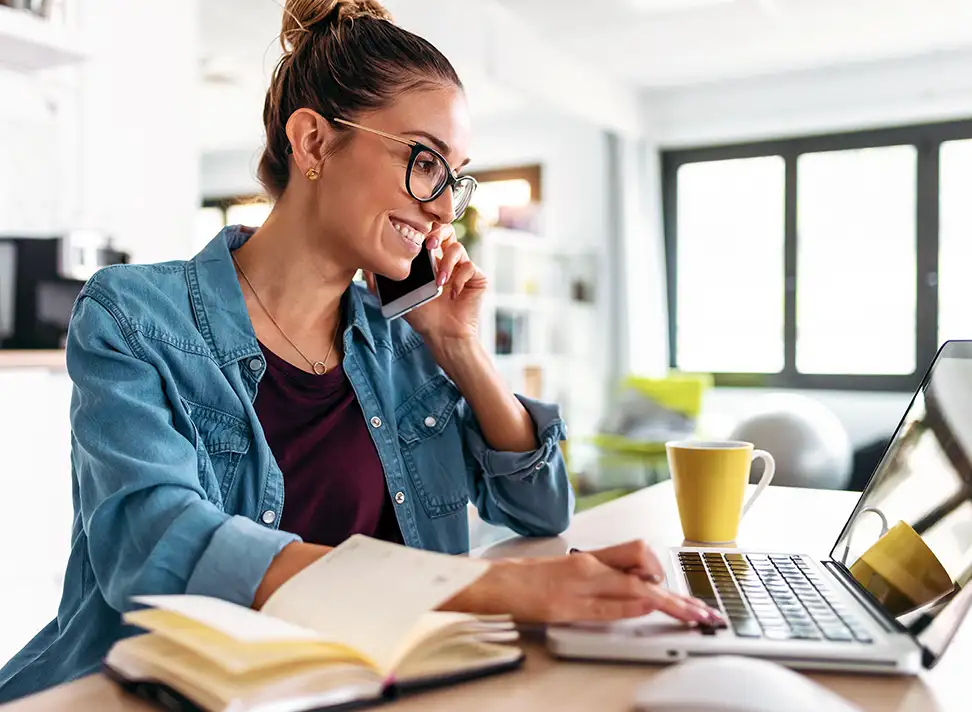 Woman Talking on the Phone While Using a Laptop